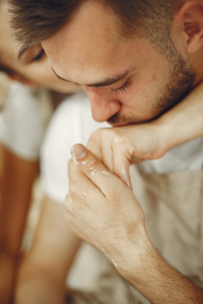 Travail créatif mutuel. Jeune beau couple en vêtements décontractés et tabliers. Les gens créant un bol sur un tour de poterie dans un studio d'argile.