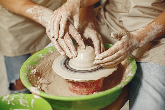 Travail créatif mutuel. Mains créant un bol sur un tour de poterie dans un studio d'argile.