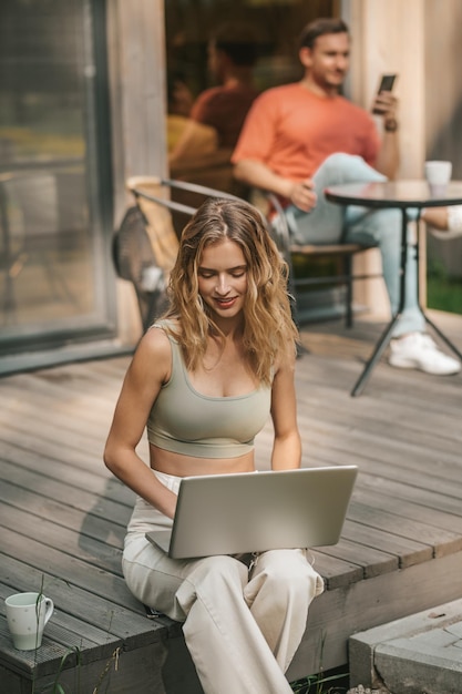 Travail à domicile. Jeune femme blonde assise dehors et travaillant sur un ordinateur portable