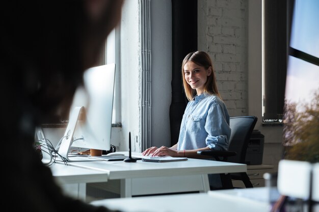 Travail de femme heureuse au bureau à l'aide d'ordinateur