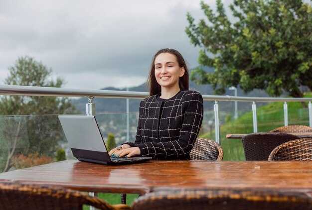 Travaillant sur un ordinateur portable, une blogueuse regarde la caméra sur fond de vue nature