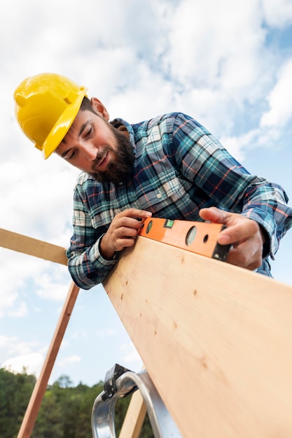 Travailleur avec casque et contrôle de niveau du bois du toit