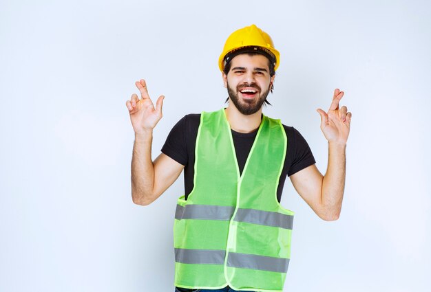 Travailleur en casque montrant un doigt croisé.