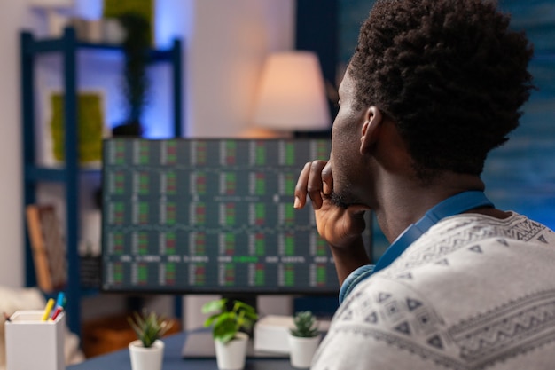 Travailleur de commerçant afro-américain vérifiant le graphique du marché boursier sur ordinateur