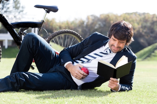 Photo gratuite travailleur concentré en lisant un livre sur l'herbe