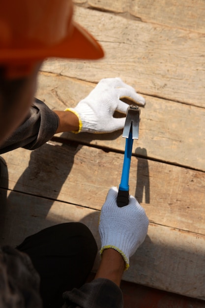 Photo gratuite travailleur de la construction à l'aide d'un marteau sur le chantier