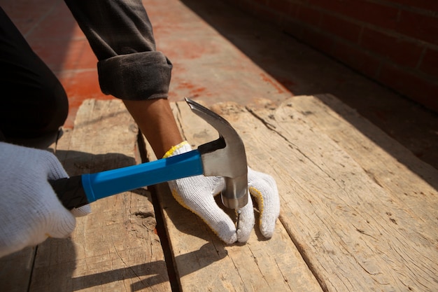 Photo gratuite travailleur de la construction à l'aide d'un marteau sur le chantier