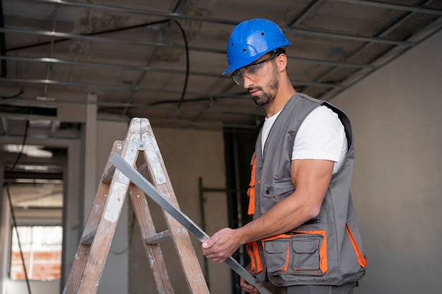 Photo gratuite travailleur de la construction à coup moyen sur une échelle