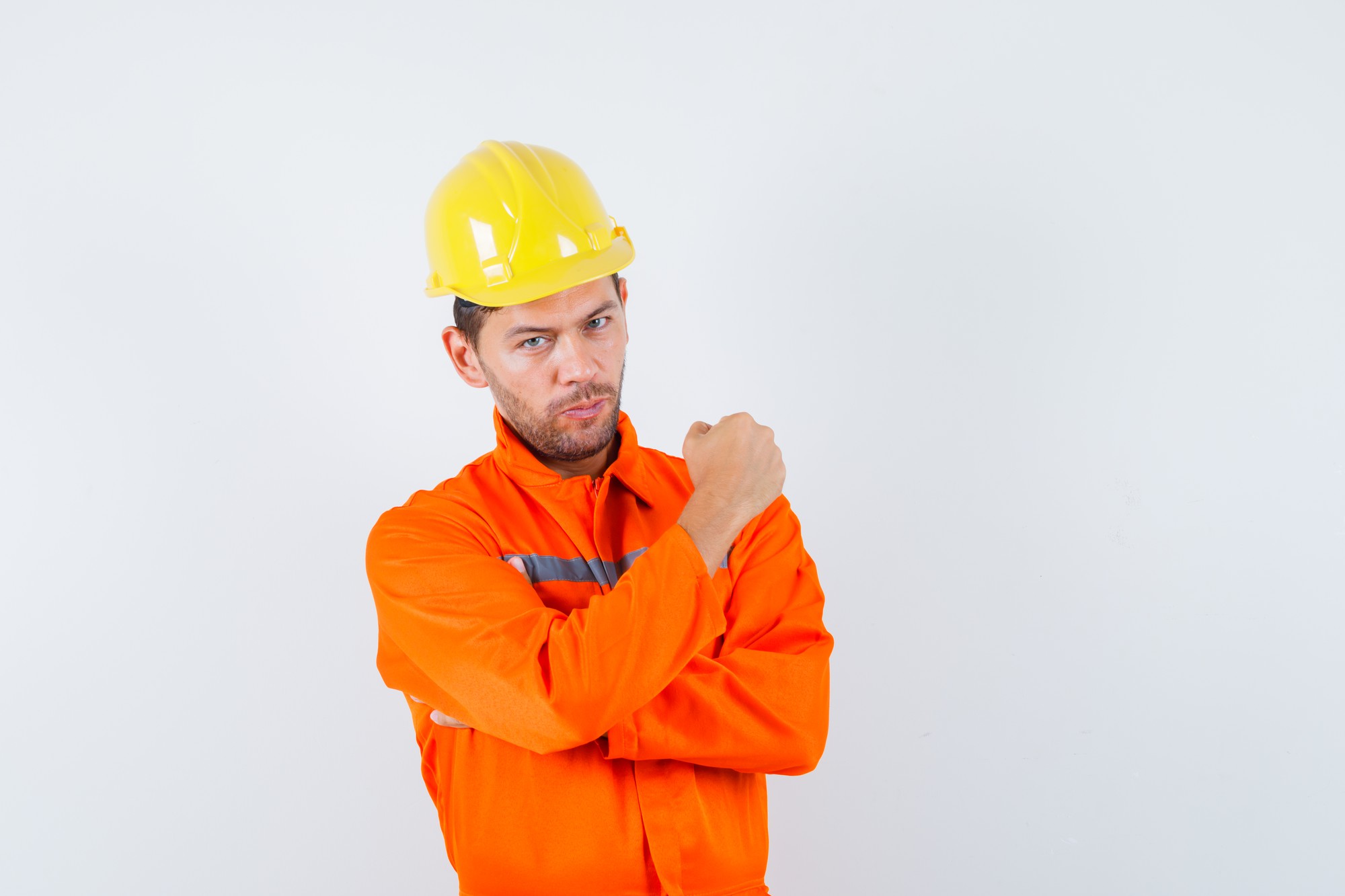 Travailleur de la construction montrant le poing fermé en uniforme, casque et à la vue de face, confiant.