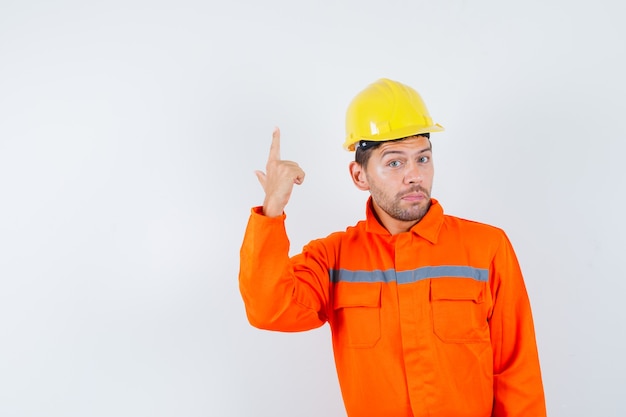 Travailleur de la construction en uniforme, casque pointant vers le haut et à la vue de face, confiant.