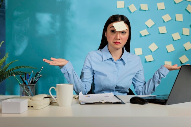 Photo gratuite travailleur de démarrage peu sûr et douteux, haussant les bras alors qu'il était assis au bureau dans l'espace de travail de bureau. femme ne sachant pas quoi faire au poste de travail attendant des instructions claires.