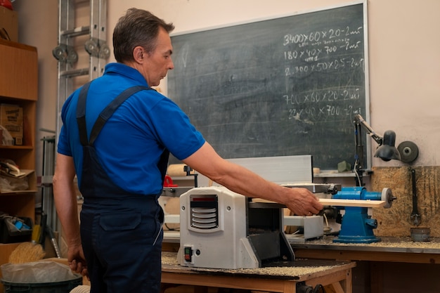 Photo gratuite travailleur du bois dans son atelier travaillant avec des outils et des équipements