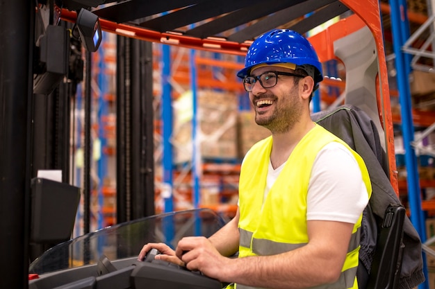 Travailleur d'entrepôt en travail de protection porter un chariot élévateur et manipuler des marchandises dans une installation de stockage