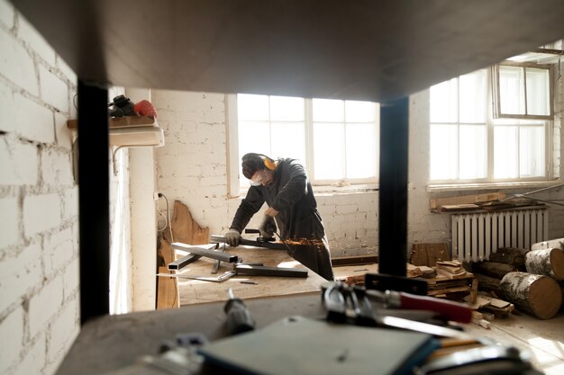 Travailleur manuel de meulage d&#39;objets métalliques en acier dans un atelier avec des outils