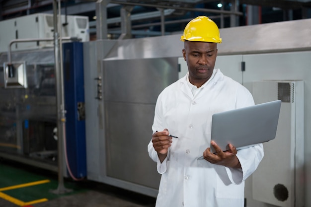 Travailleur masculin utilisant un ordinateur portable dans l'industrie manufacturière