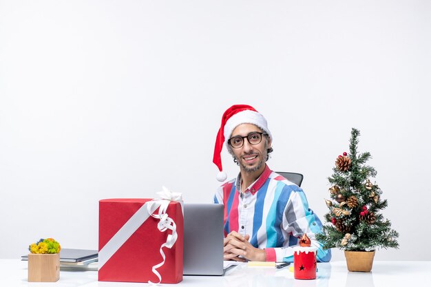 Travailleur masculin vue de face sur son lieu de travail avec ordinateur portable et fichiers travail de bureau de vacances de Noël