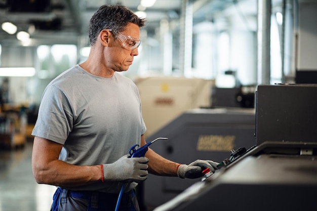 Photo gratuite travailleur métallurgiste adulte moyen utilisant une machine industrielle dans une usine