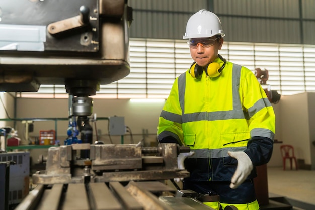 Travailleur spécialiste de l'ingénieur masculin asiatique professionnel portant un concept d'emgoneer d'usine de fabrication de machine de forage à commande manuelle uniforme