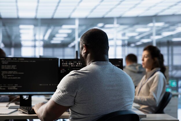 Travailleur tapant du code sur PC pour réparer les racks du centre de données