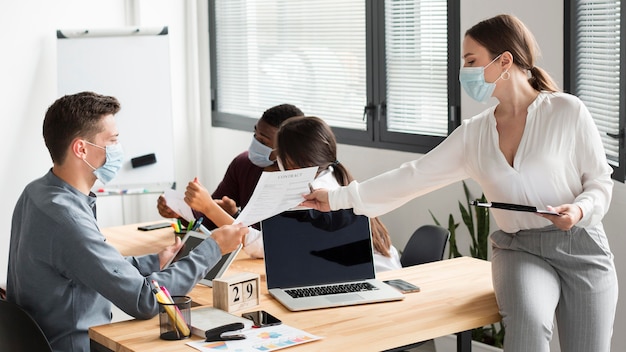 Travailleurs au bureau pendant la pandémie portant des masques médicaux