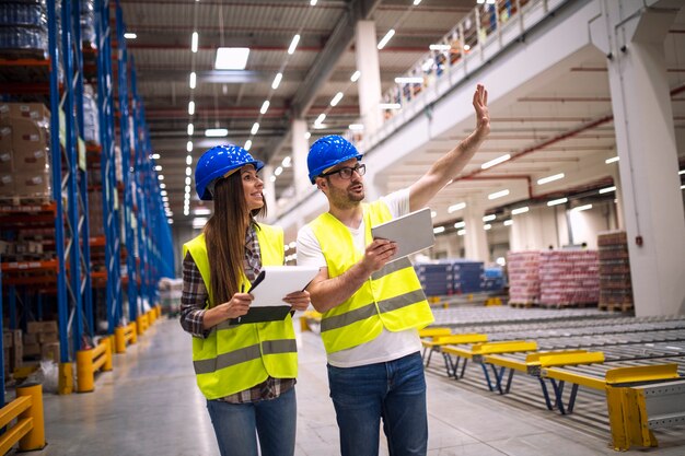 Les travailleurs d'entrepôt se consultent dans une grande zone de stockage d'usine