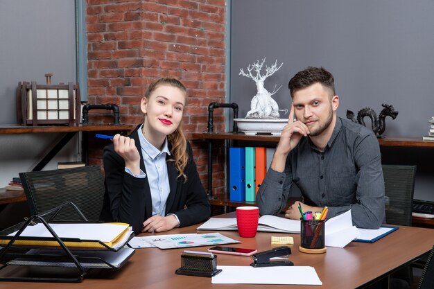 Travailleurs professionnels assidus et positifs discutant d'un problème dans les documents du bureau