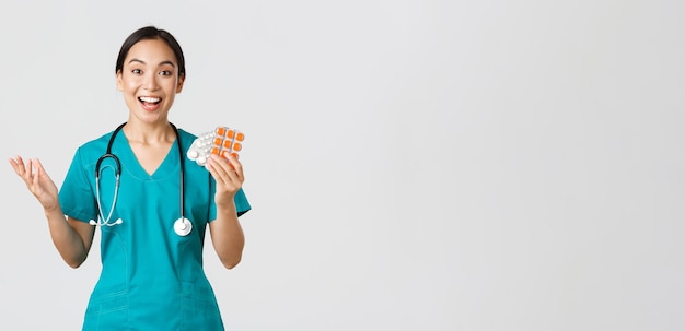 Travailleurs de la santé, prévention des virus, concept de campagne de quarantaine. Une femme médecin asiatique heureuse et excitée, une infirmière portant un masque médical montrant de nouveaux médicaments incroyables, recommande une pharmacie.