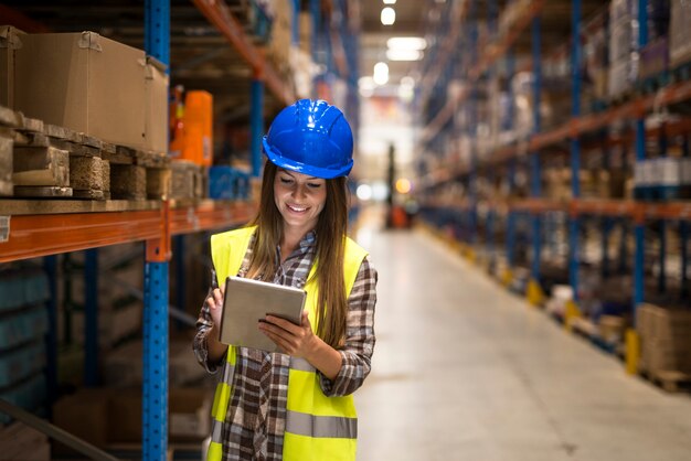 Travailleuse d'entrepôt contrôle des stocks sur tablette numérique dans la zone de stockage de l'entrepôt de distribution