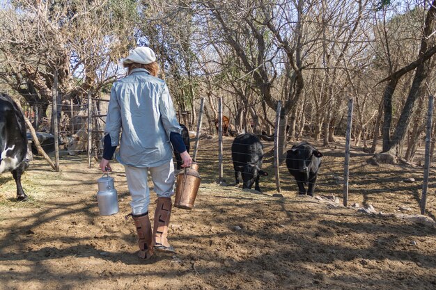 Travailleuse rurale marchant dans la campagne argentine avec des bidons de lait fraîchement traites