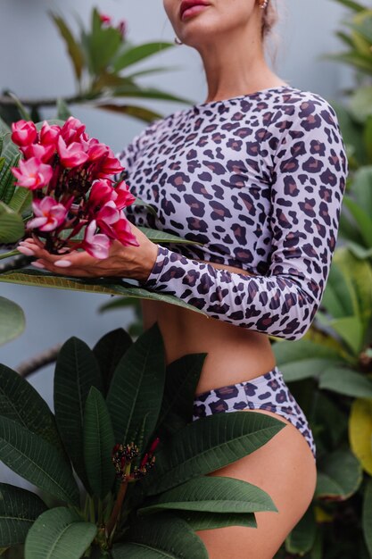 Très jolie femme caucasienne avec un corps parfaitement ajusté en maillot de bain léopard avec de belles fleurs tropicales