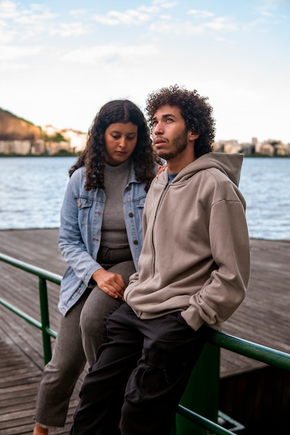 Triste couple assis près du quai à côté du lac