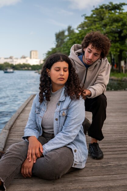 Triste couple assis près du quai à côté du lac