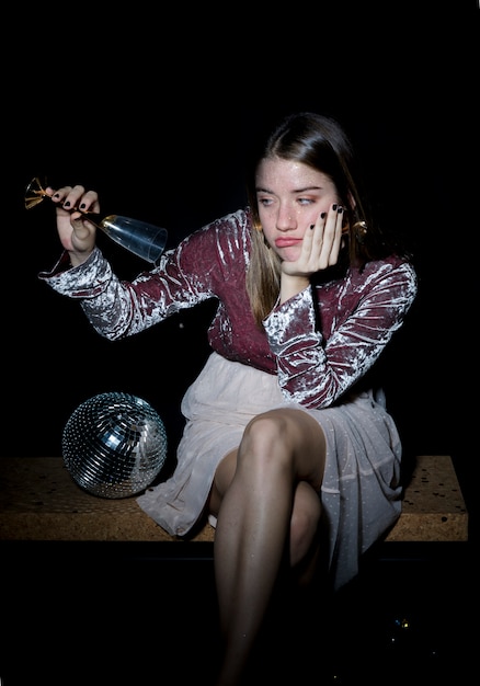 Triste femme assise avec un verre de champagne à la main