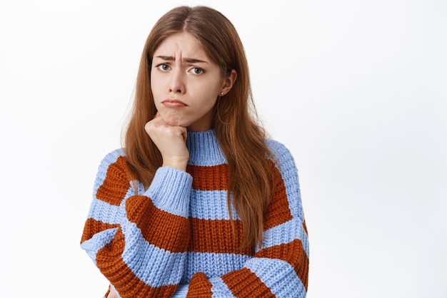 Triste fille mécontente boudant l'air offensée ou insultée d'être en colère contre une situation injuste regardant fixement déçu debout sur fond blanc