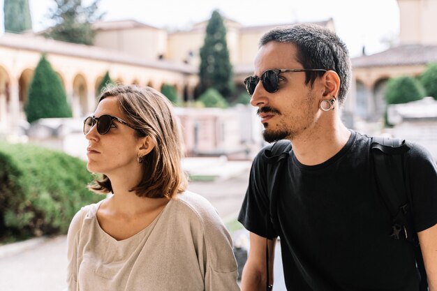 Triste jeune couple avec des lunettes de soleil faisant face au cimetière de Bologne, Italie