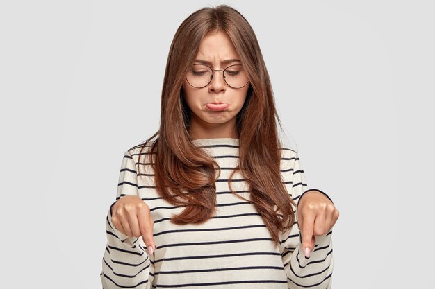 triste, jeune femme, à, lunettes, poser, contre, mur blanc