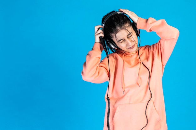 Triste jeune fille écoutant de la musique et pleurant sur fond bleu Photo de haute qualité