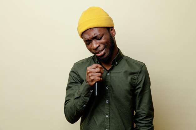 Triste jeune homme afro-américain en chapeau portant une chemise verte parle sur haut-parleur isolé sur fond blanc