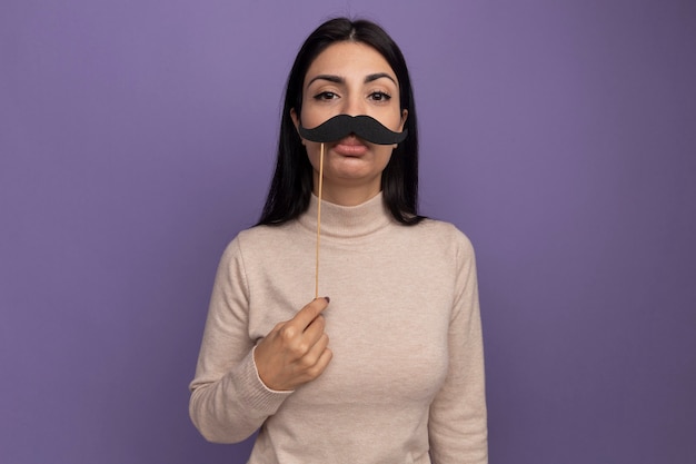 Photo gratuite triste jolie fille de race blanche brune tient une fausse moustache sur bâton violet