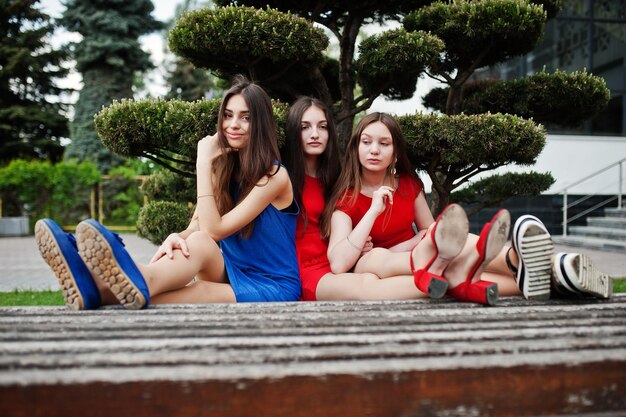 Trois adolescentes en robes bleues et rouges posées en plein air