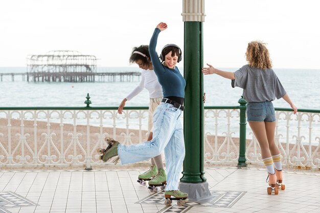 Trois amies avec des patins à roulettes roulant à l'extérieur