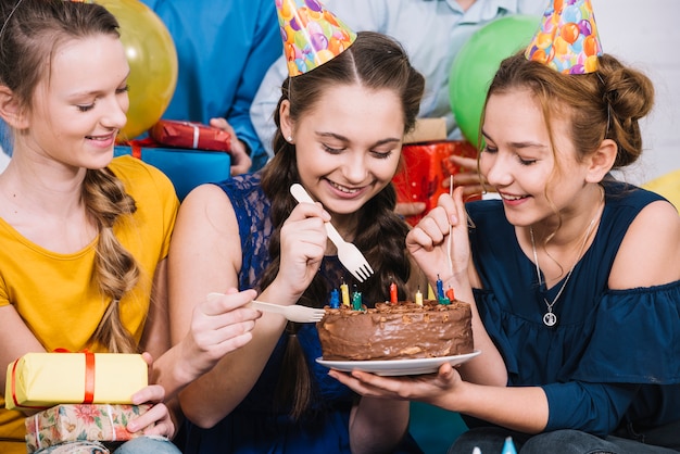 Trois amies en train de manger le gâteau avec une fourchette