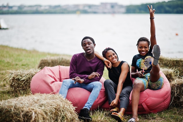 Trois amis afro-américains se détendent et s'assoient sur des poufs en plein air