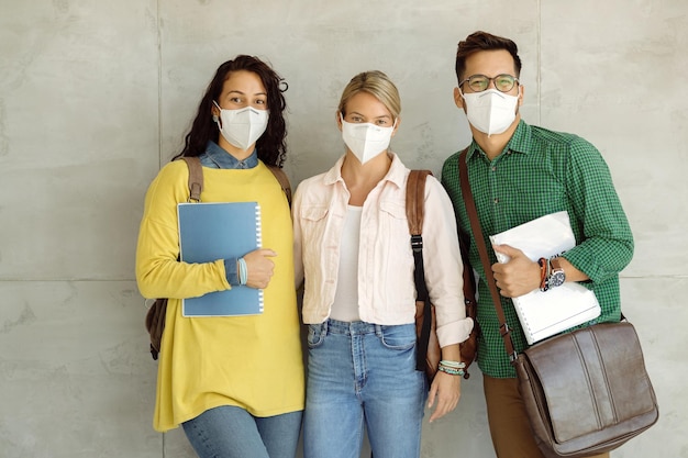 Trois amis du collège portant un masque protecteur dans le couloir de l'université