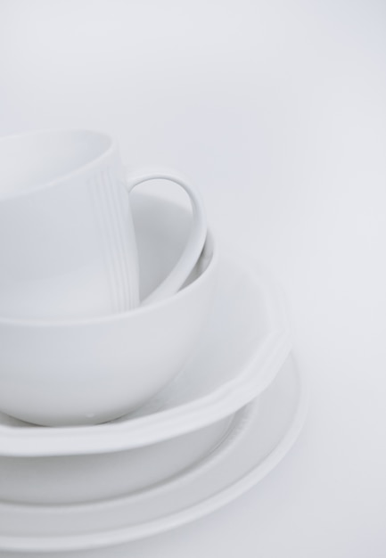 trois assiettes blanches et une tasse sur un fond blanc