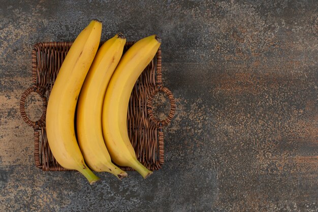 Trois bananes mûres dans un panier en bois.