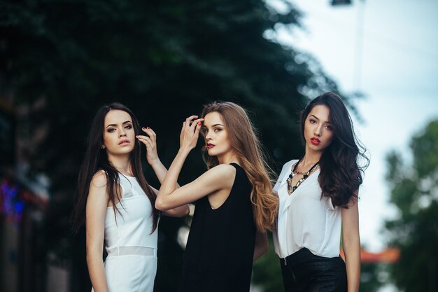 Trois belles jeunes filles posant dans une rue de la ville la nuit