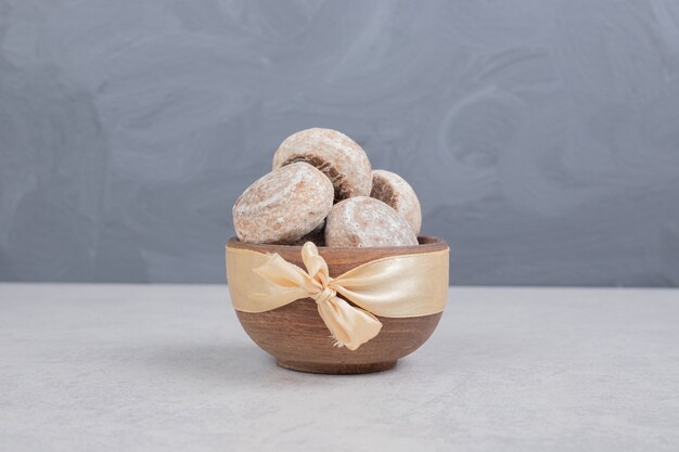 Trois biscuits sucrés avec un arc d'or sur un bol en bois