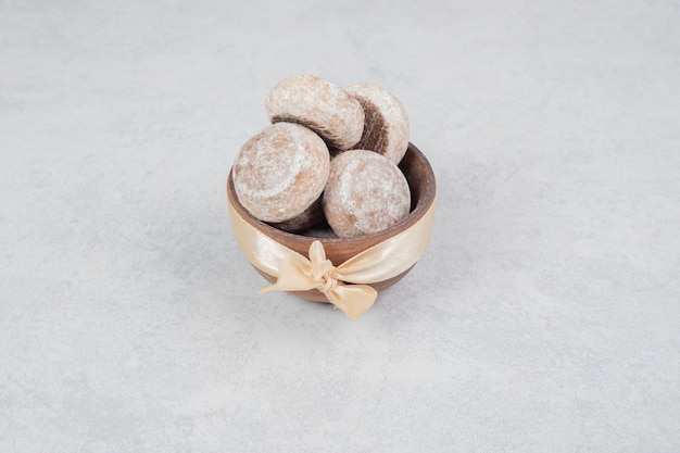 Trois biscuits sucrés avec un arc d'or sur un bol en bois