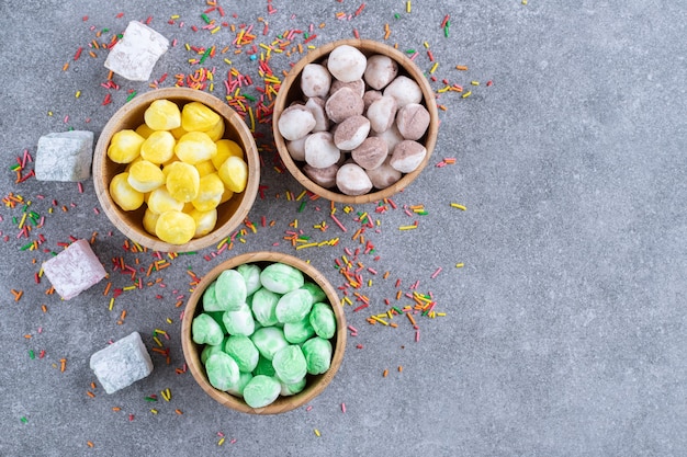 Photo gratuite trois bols de bonbons colorés sur une surface en marbre